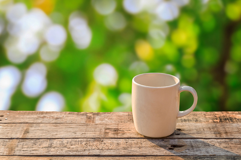 White coffee cup on wooden table at morning sunlight and bokeh b
